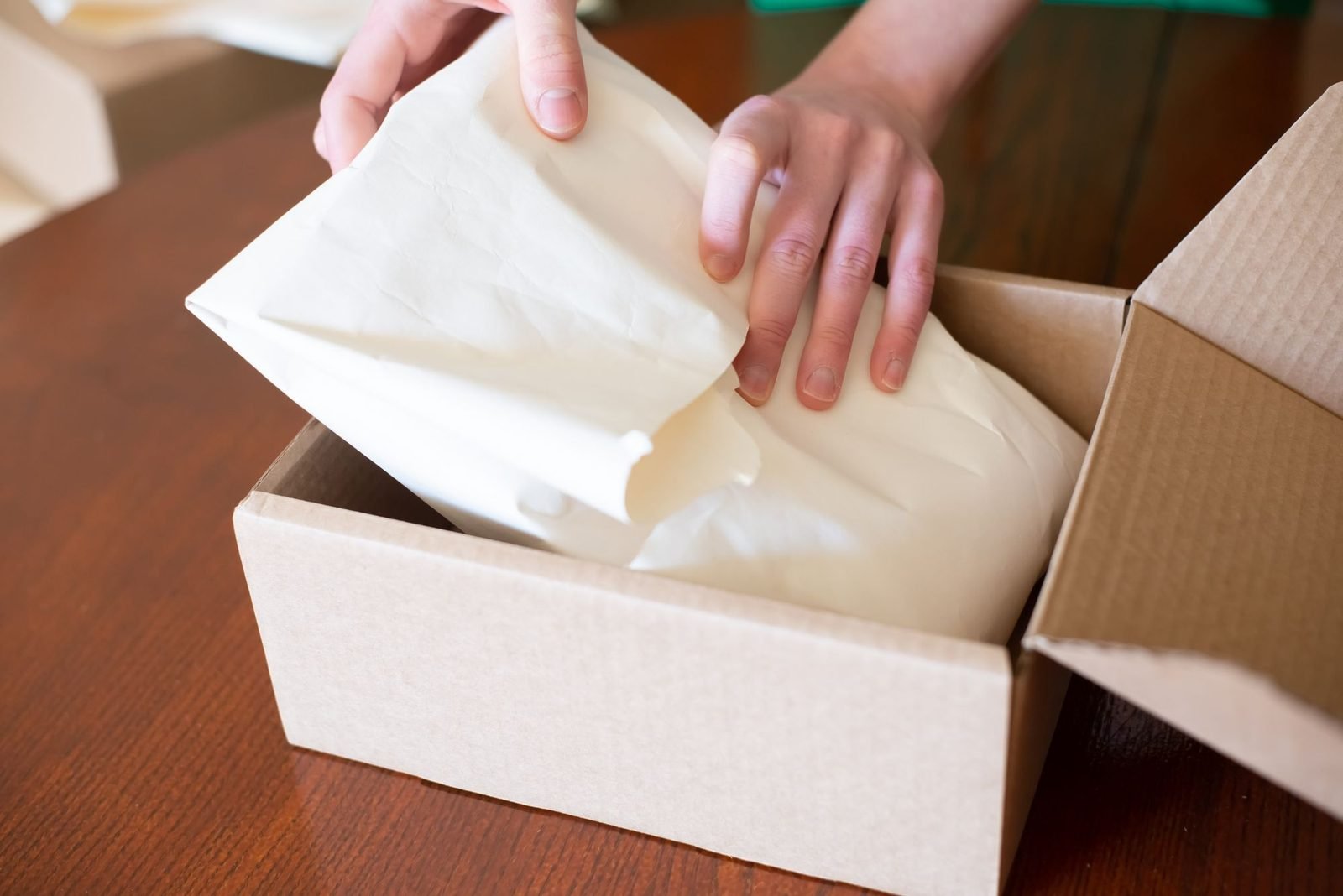 Mãos embalando um pedido em uma caixa de papelão