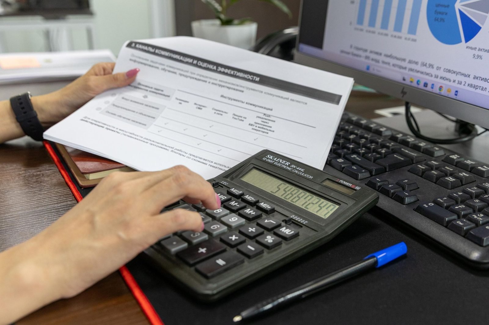 Mãos com um documento financeiro e uma calculadora sobre a mesa