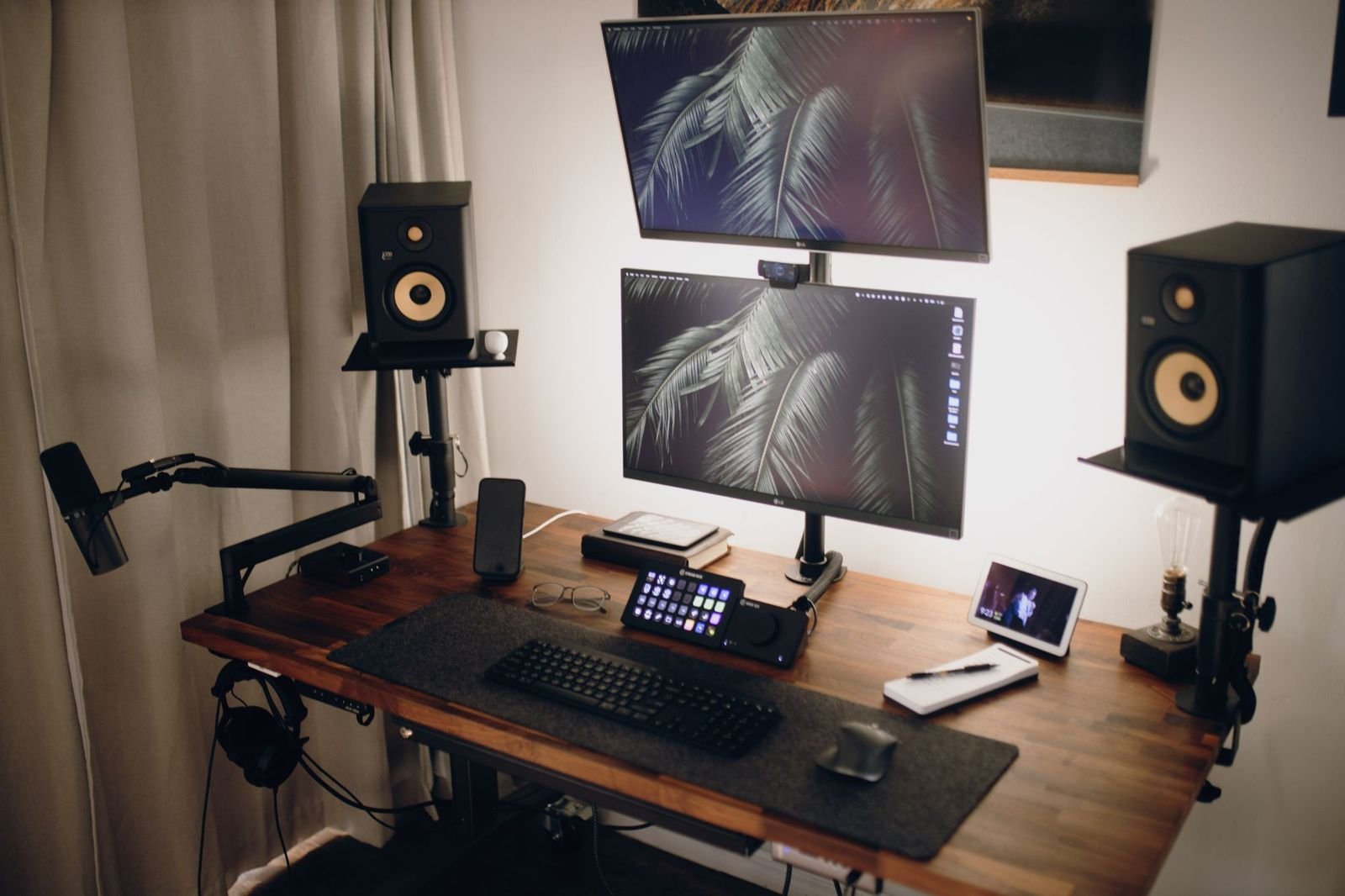 Mesa de streaming com dois monitores, microfone e caixas de som