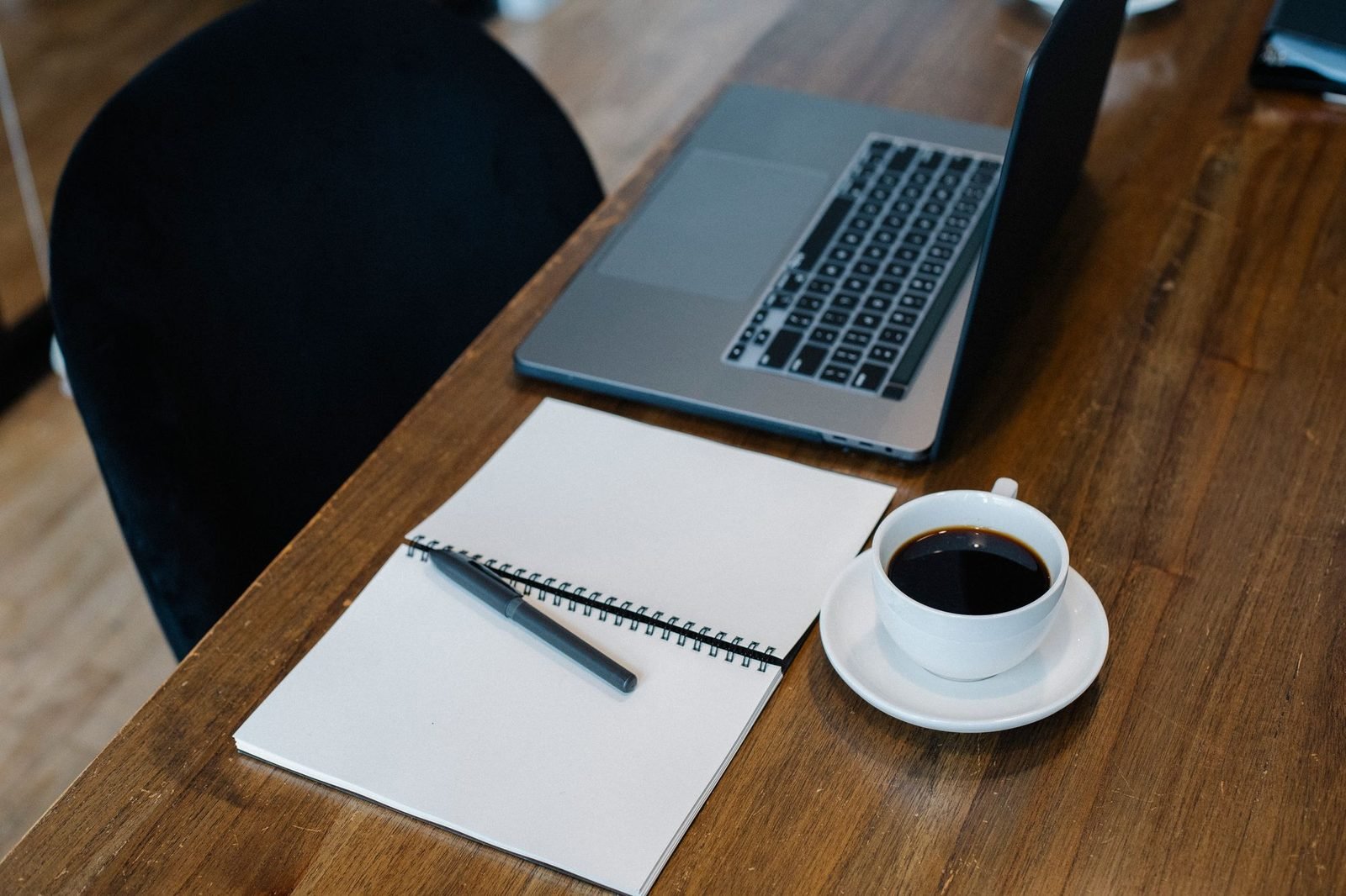 Mesa de trabalho com notebook, caderno e xícara de café