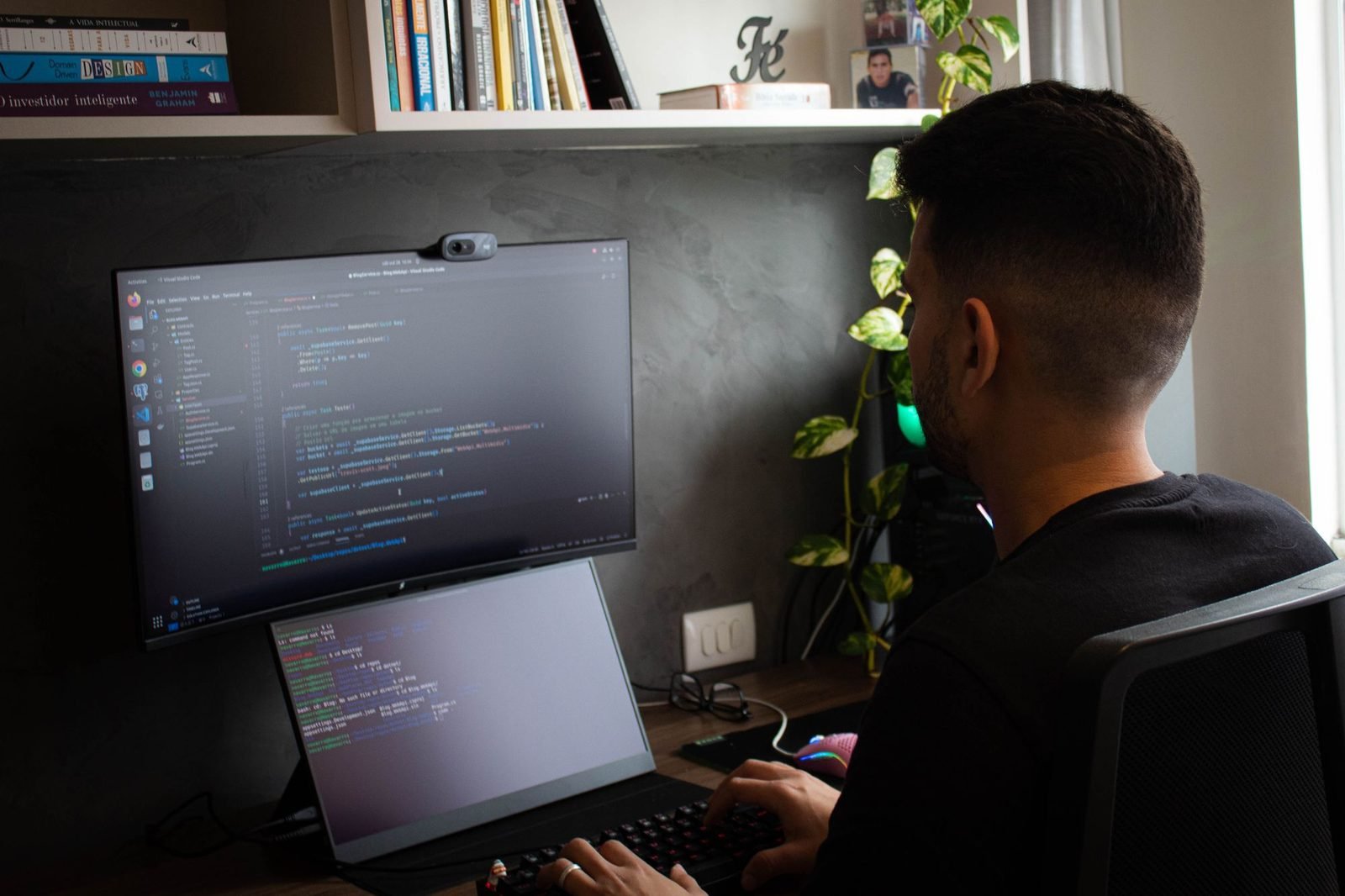 Programador de costas, diante de dois monitores com código