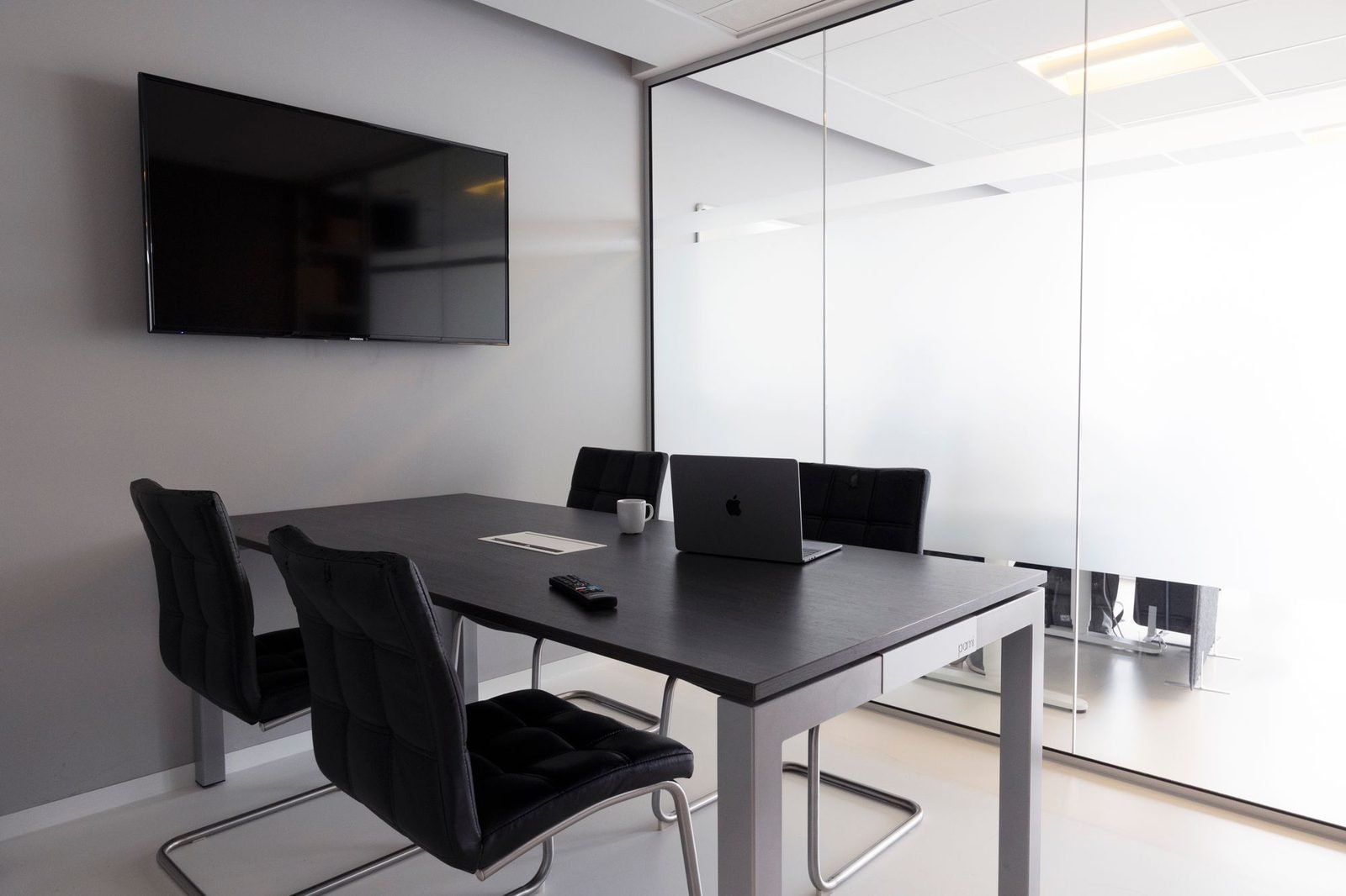 Sala de reunião vazia, com mesa, cadeiras e parede de vidro